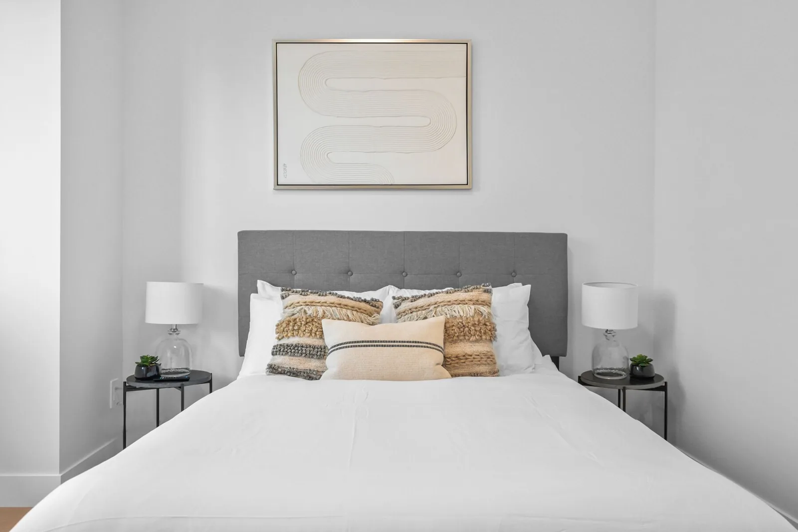 Bedroom with white bedding and a framed print above the bed